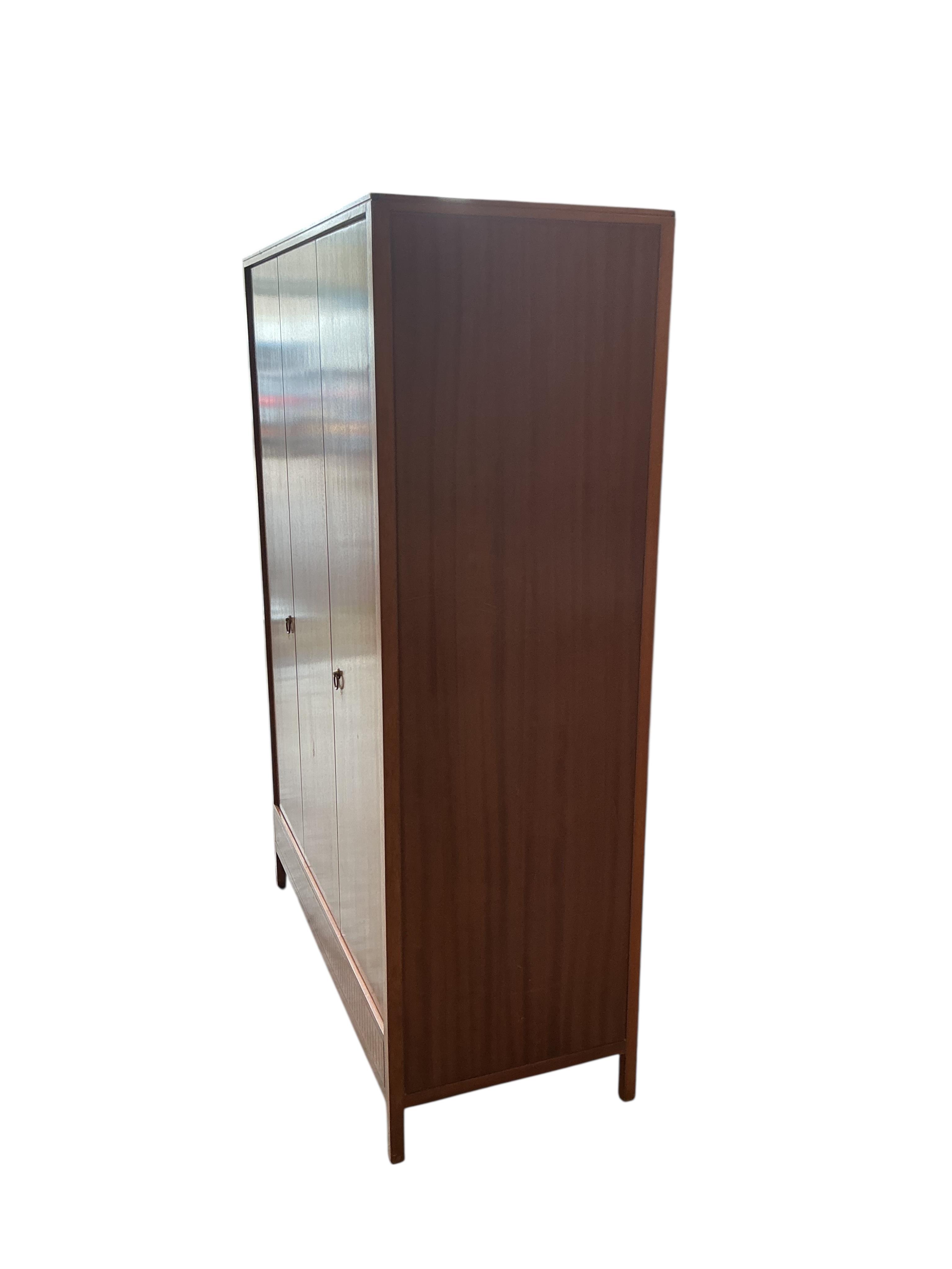 A Loughborough For Heals brass inlaid teak four piece bedroom suite comprising: triple wardrobe, width 120cm, depth 54cm, height 176cm, two chests of drawers and a toilet mirror